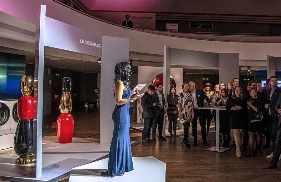 Viele Menschen starren auf die Hauptbühne und eine Frau, die vor dem OLED TV von lg signature steht, spricht zu allen auf der Kunstwoche in Deutschland