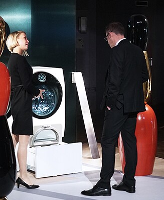 Auf der Kunstwoche in Deutschland unterhalten sich mehrere Leute vor der Waschmaschine von lg signature 