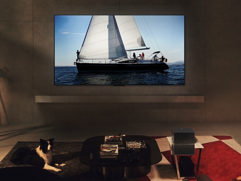 LG OLED evo M4 og LG Soundbar i et moderne hjem om natten. Billedet på skærmen af en sejlbåd på havet vises med ideelle niveauer for lysstyrke.