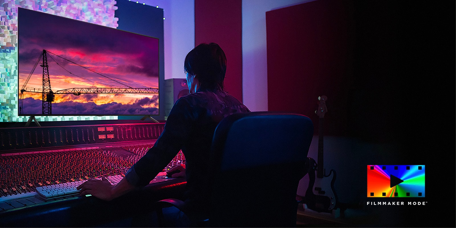 A man in a dark editing studio looking at an LG TV displaying the sunset. On the right bottom of the image is a FILMMAKER Mode logo.