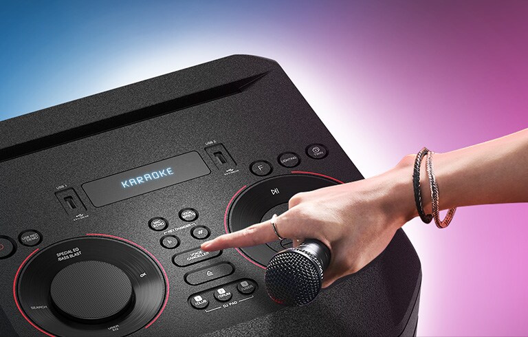 A hand holding a microphone tries to press the Voice canceller button on the top of LG XBOOM.