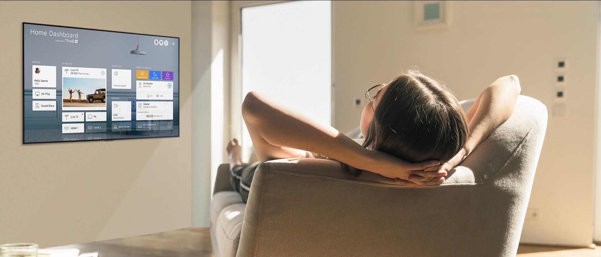 Mujer recostada en un sofá diciéndole a la TV que baje la temperatura con el Panel de inicio en la pantalla de la TV