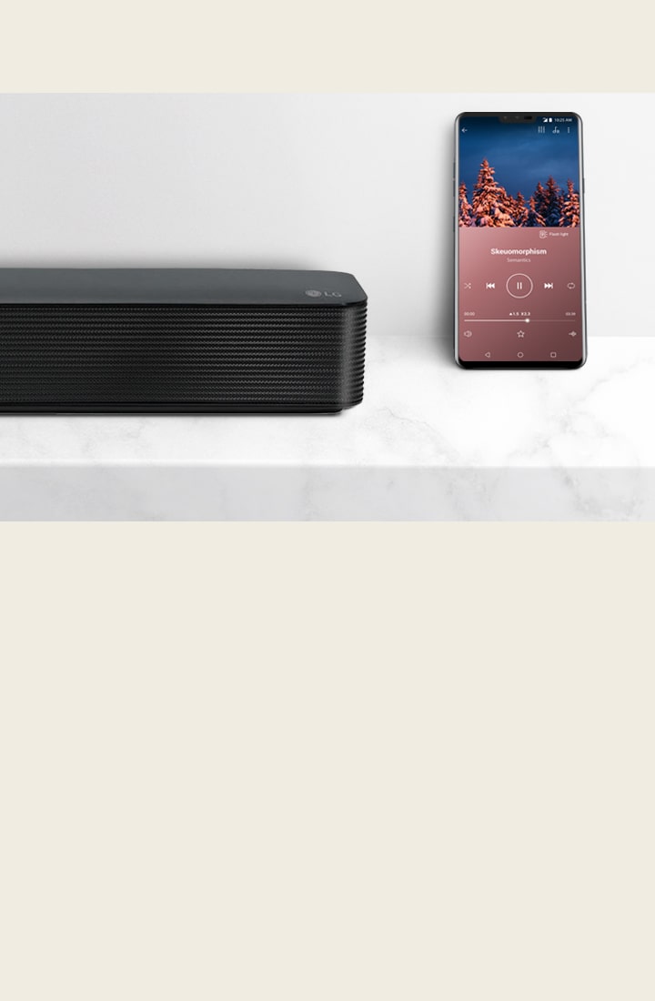 LG Soundbar ribakõlari parempoolne lähivaade nutitelefoni kõrval. Valgel riiulil on kaks seadet.