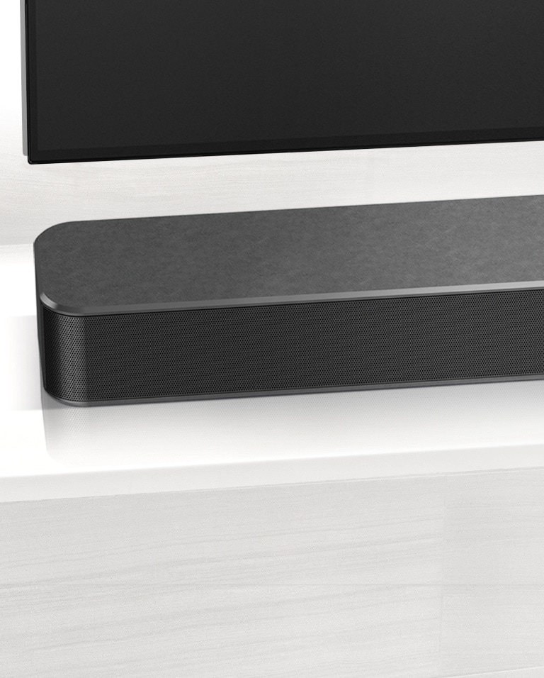 Close-up of LG Soundbar left corner. Bottom left side of TV is also visible. 