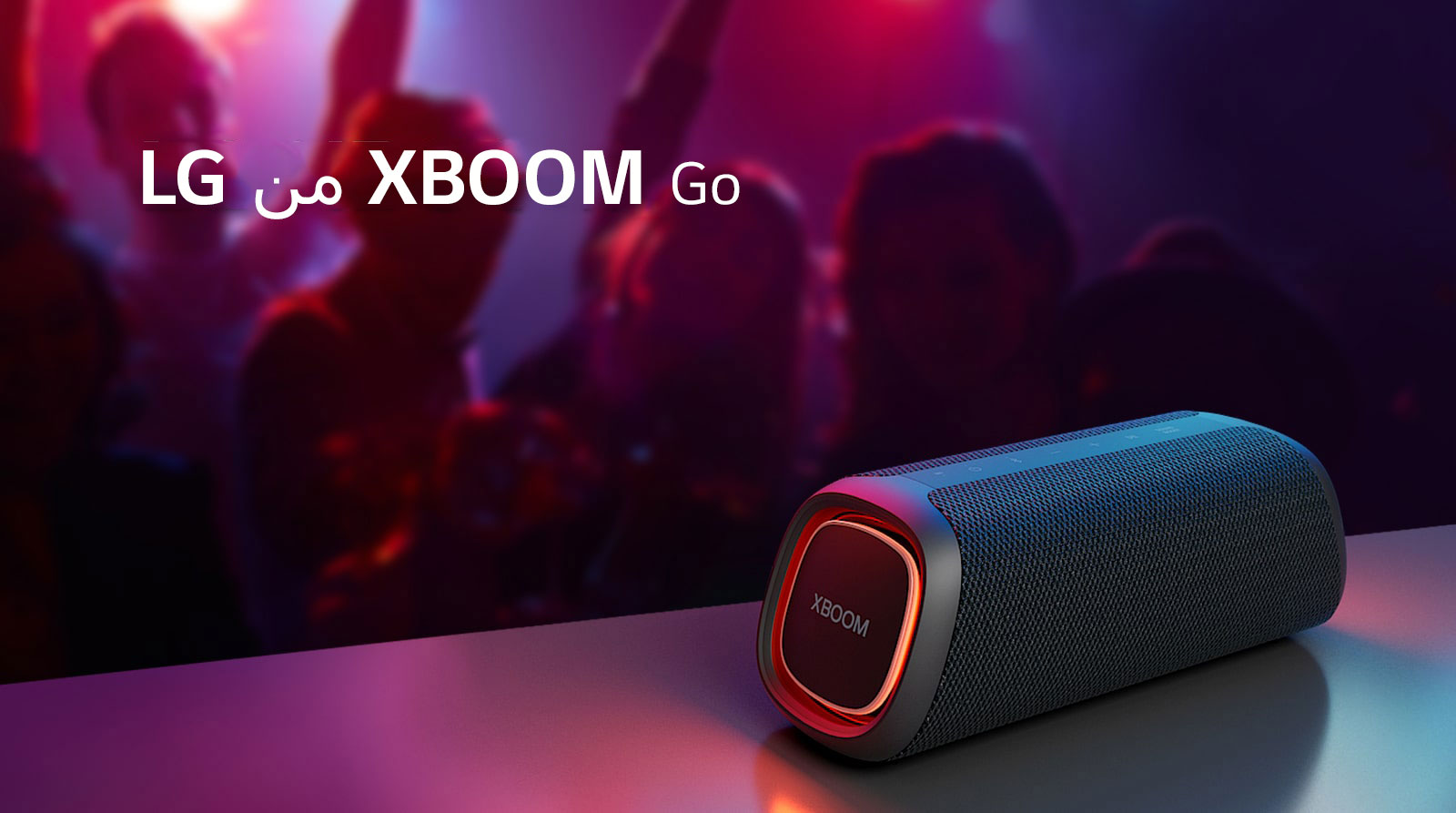 مكبر الصوت XBOOM Go XG5 من LG موضوع على طاولة معدنية ومضبوط على وضع الإضاءة البرتقالية. أشخاص يستمتعون بالموسيقى من خلف الطاولة.