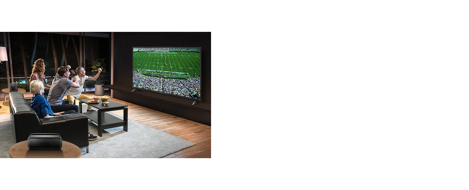 الأشخاص الذين يشاهدون الألعاب الرياضية على التلفزيون في غرفة المعيشة مع مكبرات الصوت الخلفية التي تعمل بتقنية البلوتوث.