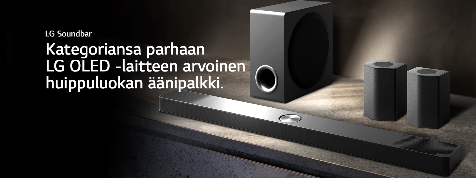 LG Soundbar, takakaiuttimet ja subwoofer on asetettu kulmasta näkyvään ruskeaan puuhyllyyn mustassa huoneessa, jonka ainoa valaistus kohdistuu äänijärjestelmään.