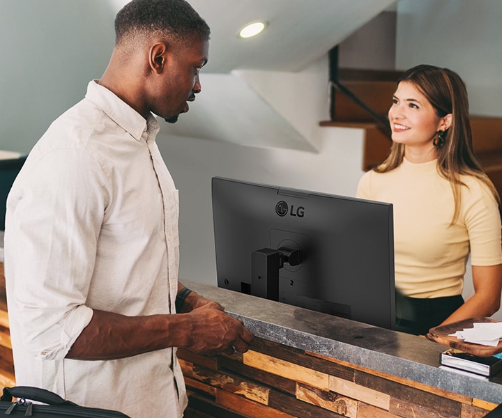 A female receptionist is talking to a man at the front desk.