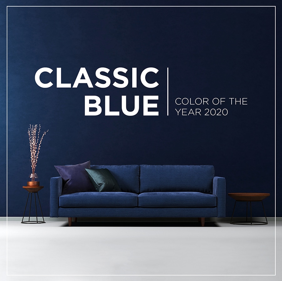 There is a blue couch in front of wall of the color of classic blue.