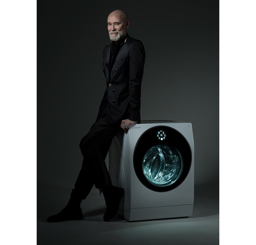 Fashion designer Lars Wallin leaning on a LG SIGNATURE Washing Machine, his signature written on the imagge