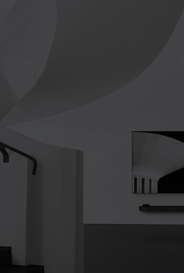 a black and white image of lg signature oled tv which is hung on the wall and to the left there is a spiral staircase