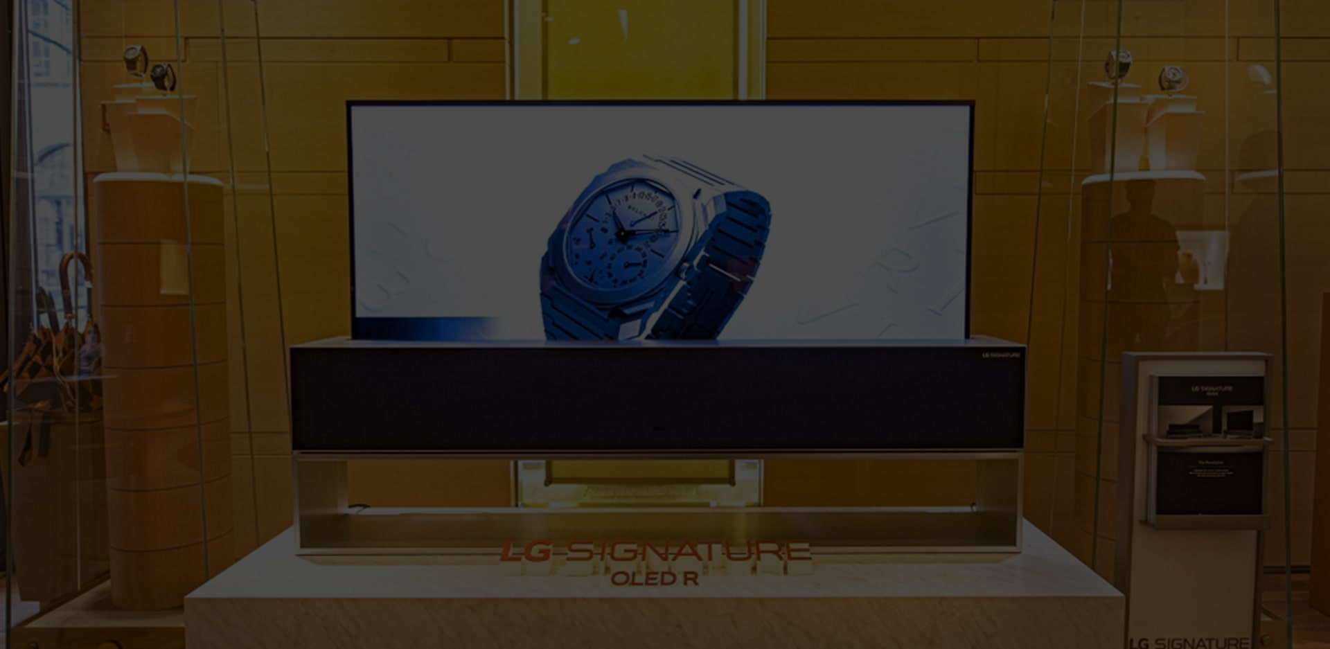 Article title overlaid on an image of a Rollable OLED TV R showing a Bulgari watch onscreen.