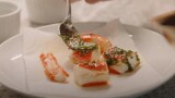 Thumbnail showing a close up shot of several small pieces of food arranged artfully on a white plate. (play the video)