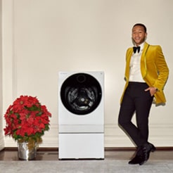 John Legend smiling and standing beside a washer