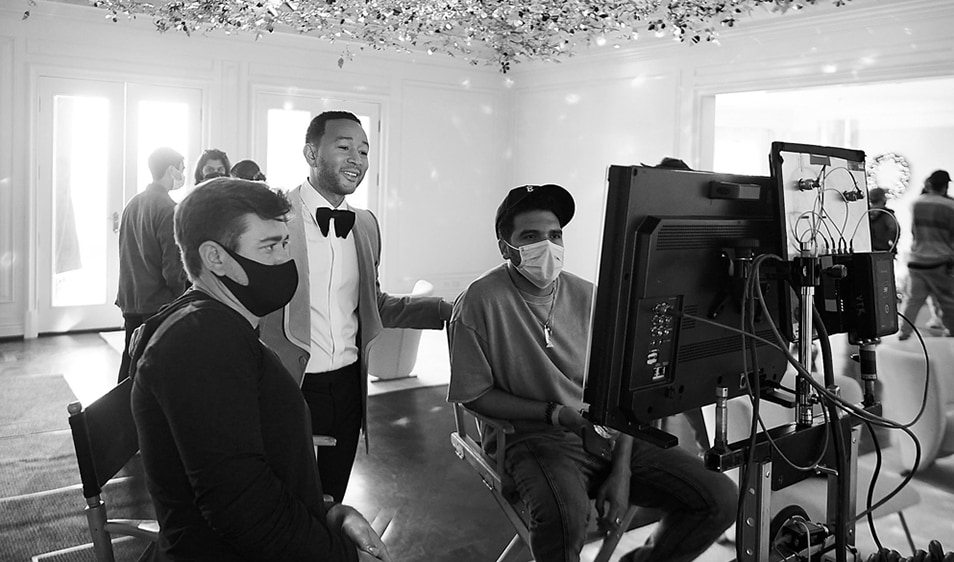 John Legend looking over the shoulders of the camerapeople at a screen