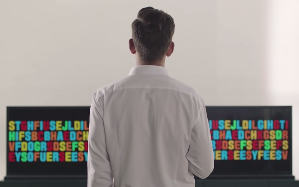 Ένας άνδρας στέκεται μπροστά από πολλαπλές LG τηλεοράσεις OLED.