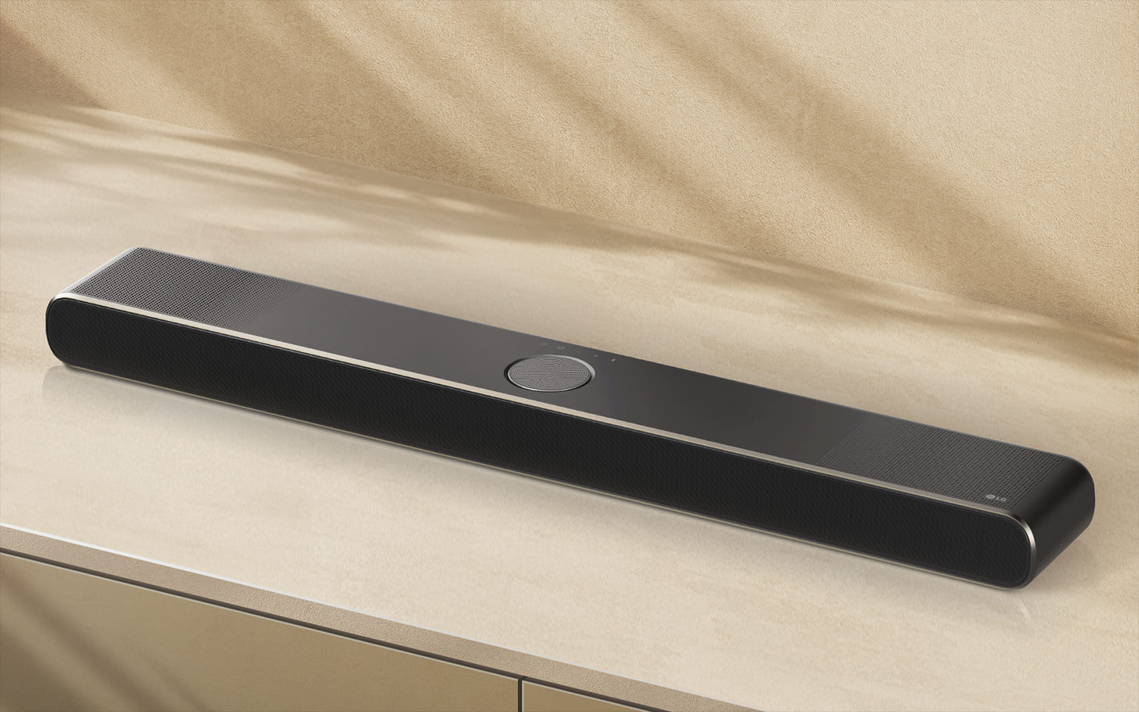 LG Soundbar bézs színű felületen, bézs színű háttér előtt, légi perspektívában. 