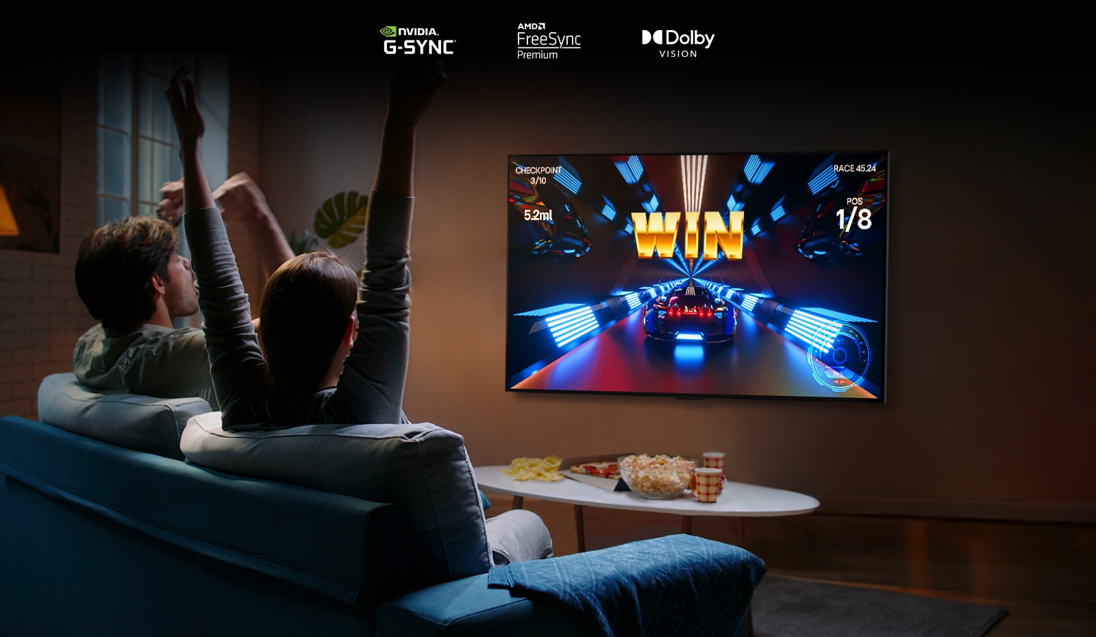 Dve osebi sedita na kavču v dnevni sobi in igrata dirkalno igro na televizorju LG OLED G2 z igralnim krmilnikom