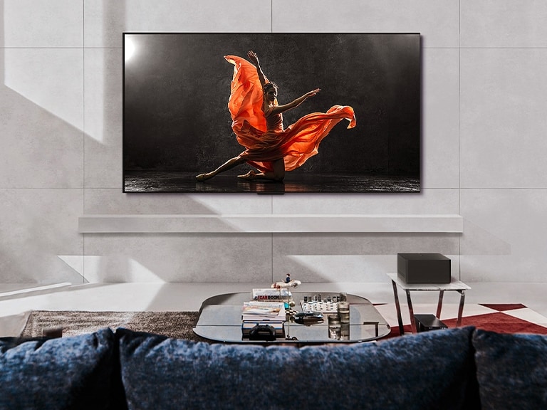 LG SIGNATURE OLED M4 TV és LG Soundbar hangprojektor egy modern nappaliban napközben. A sötét színpadon táncost ábrázoló képernyőkép az ideális fényerősséggel jelenik meg.