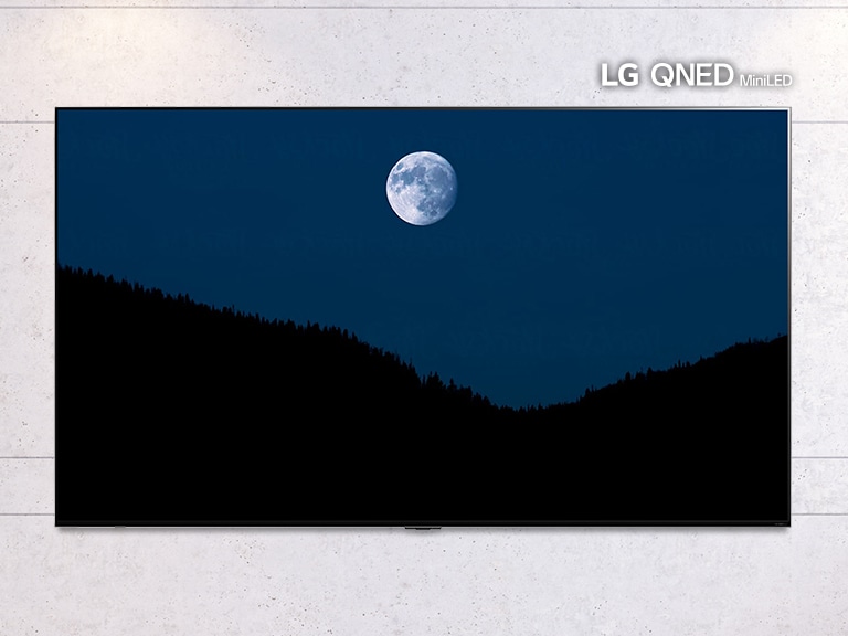 A görgethető képen egy falra szerelt TV látható, a képernyőn a hegyek fölött világító Holddal. A kép egy normál méretű TV és egy nagy képernyős LG QNED MiniLED TV között váltakozik.