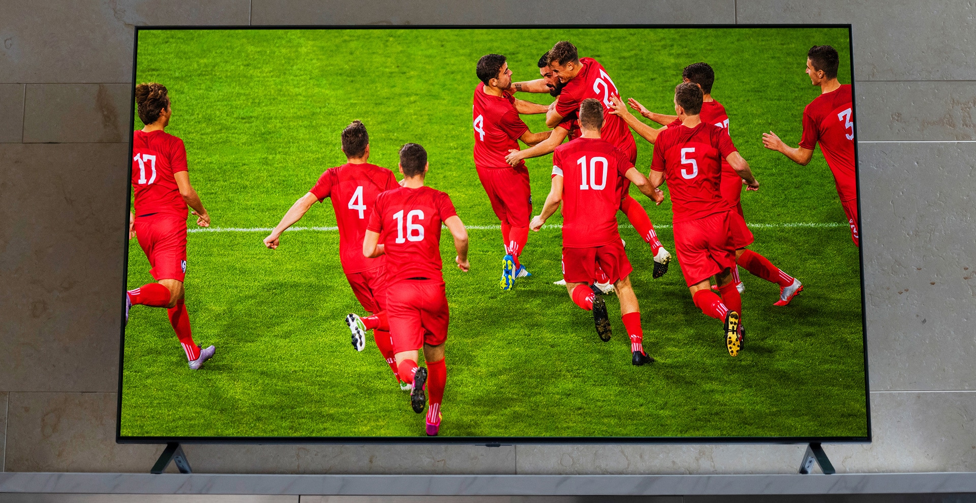 Nanocell TV a TV-állványon. Futballjátékosok ünnepelnek.