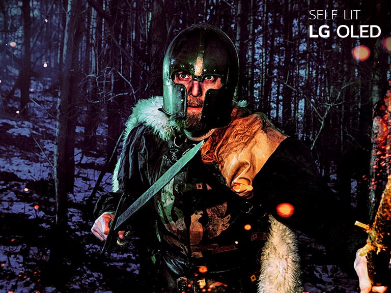 مقایسه کنار هم LCD/LED و LG OLED در رابطه با بازتولید رنگ از طریق تصویر مردی که در جنگلی زمستانی زره پوشیده است