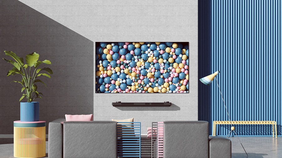 La TV OLED LG SIGNATURE è montata su una parete con delle palline colorate.