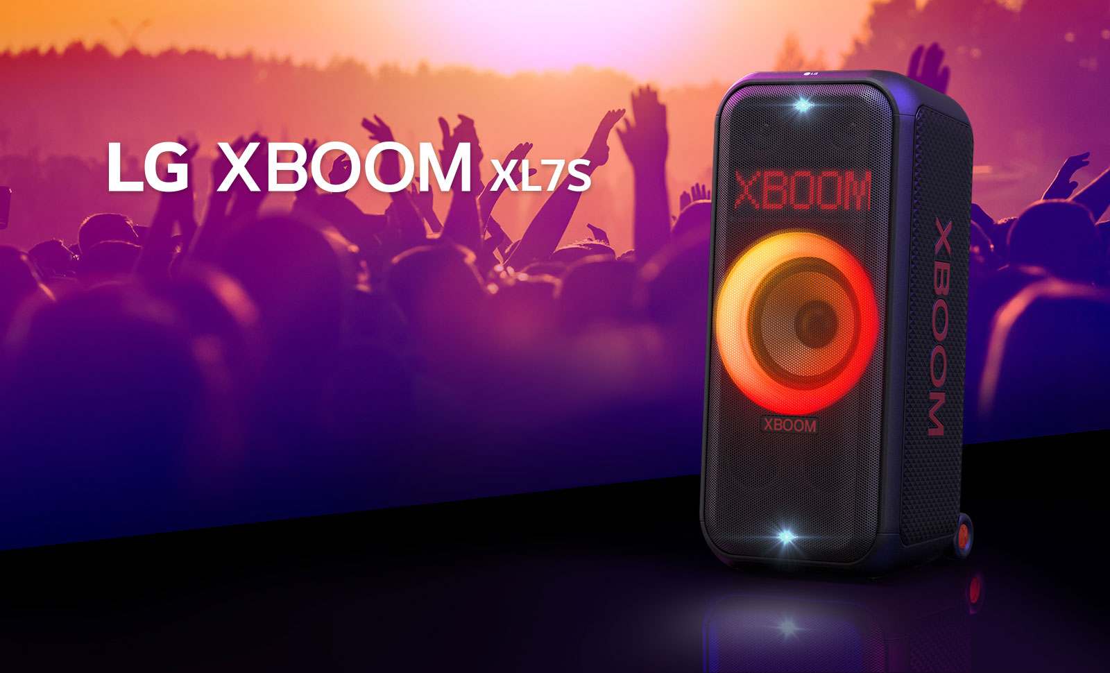 LG XBOOM XL5S padėtas ant scenos ir jame įjungtas raudonos bei oranžinės spalvų pereinantis apšvietimas. Už scenos žmonės mėgaujasi muzika.