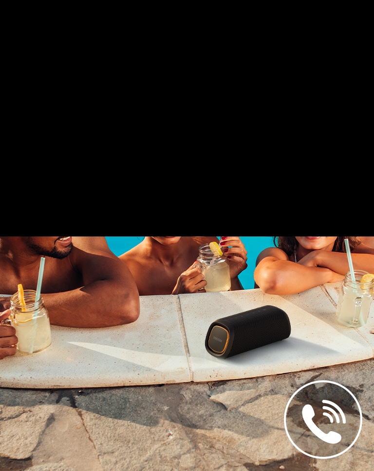 LG XBOOM Go XG7 ir novietots pie baseina. Trīs cilvēki runā pa skaļruni baseinā.