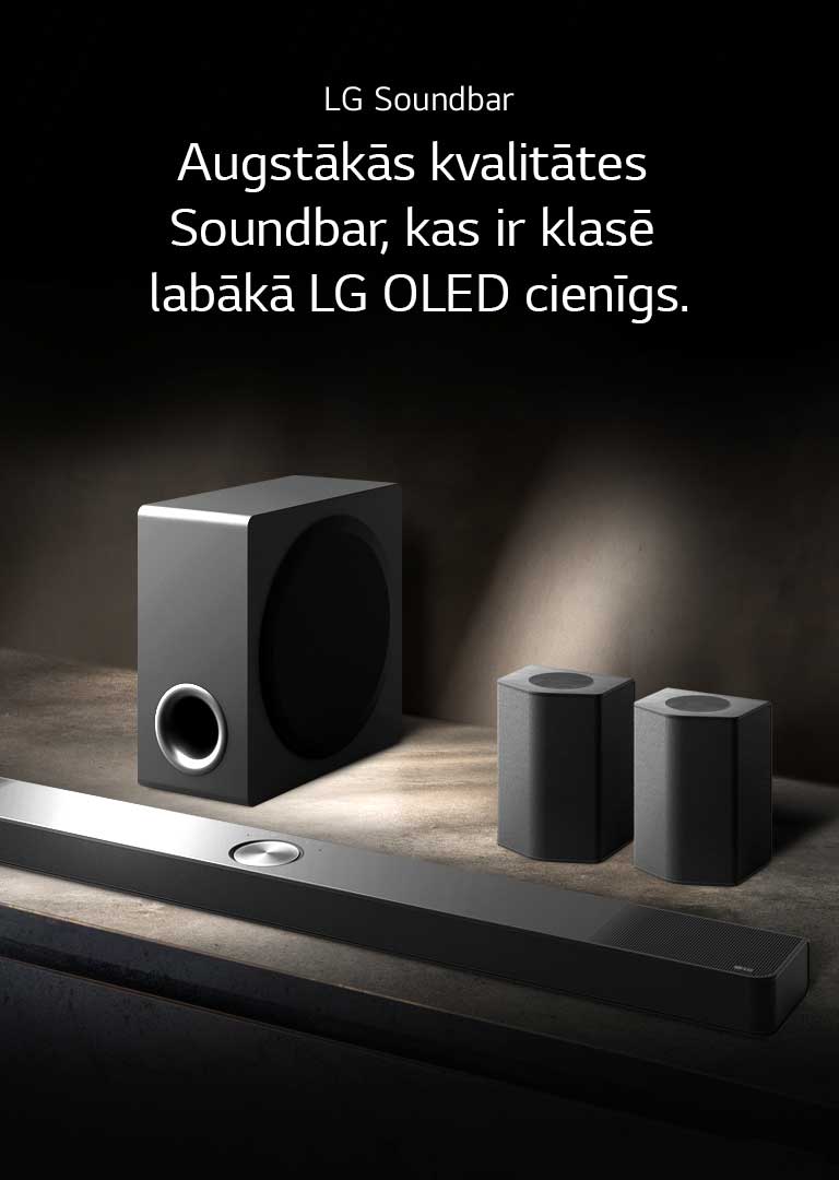 LG Soundbar, aizmugurējie skaļruņi un zemfrekvences skaļrunis ir novietoti leņķiskā perspektīvā uz brūna koka plaukta melnā telpā, ko ieskauj tumsa, un gaisma izplūst tikai pār skaņas sistēmu.