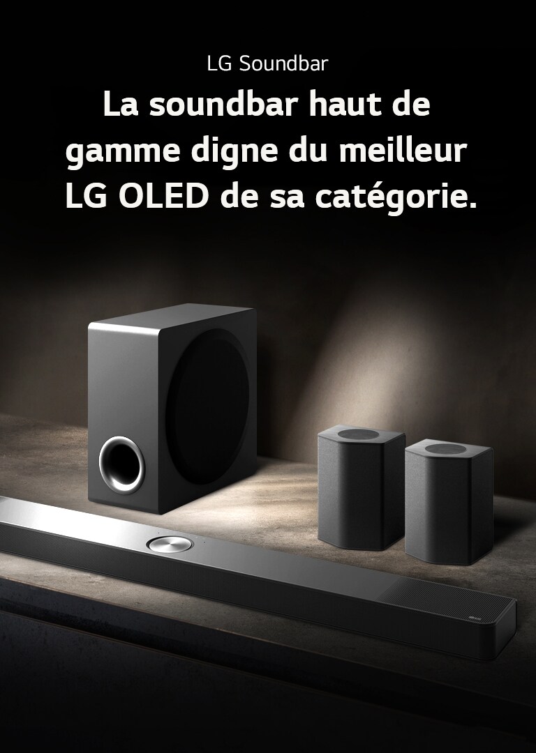 LG Soundbar, enceintes arrière et caisson de basse installés en biais sur une étagère en bois marron dans une pièce obscure, avec une lumière qui n’éclaire que le système audio