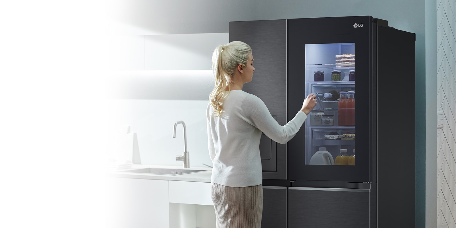 An image shows a woman at her InstaView refrigerator with knocking motion. The interior lights up and she can see the contents of her fridge without opening the door. 