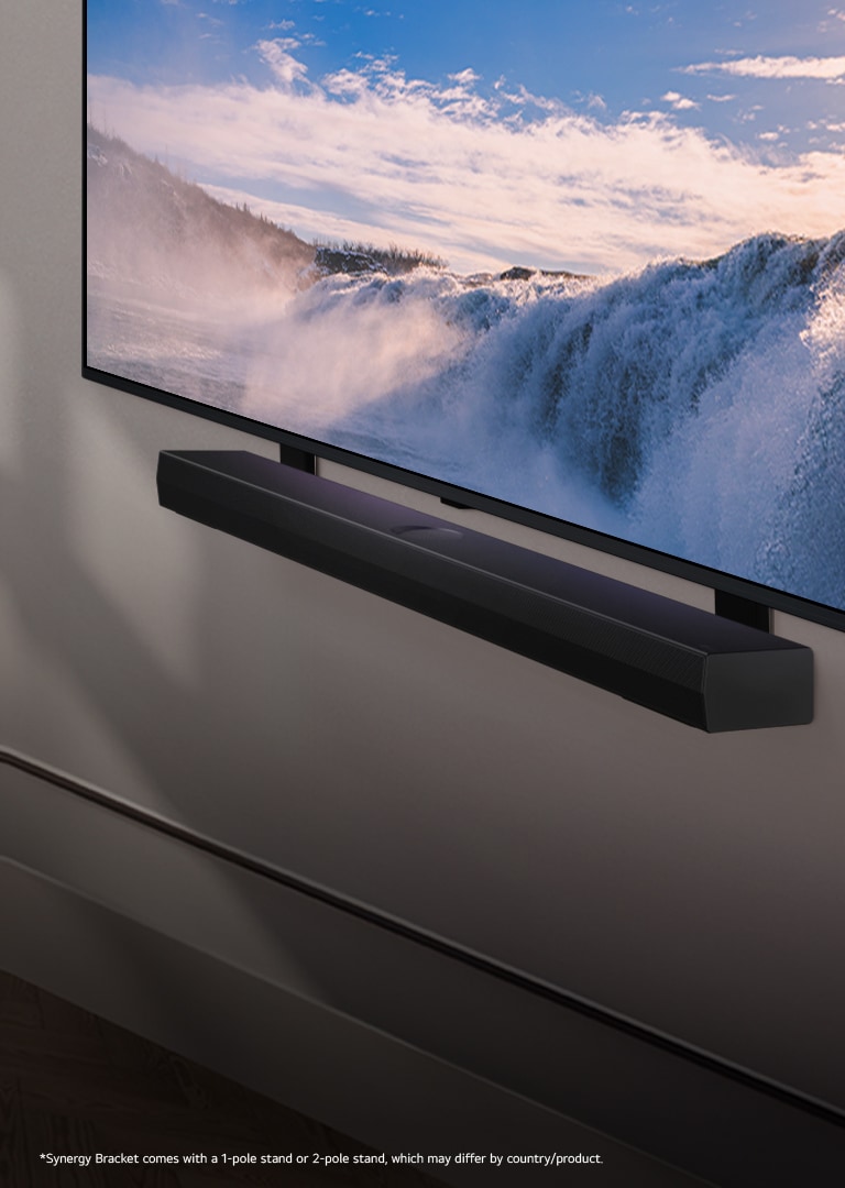 LG TV and Soundbar are placed within an angled perspective mounted on a wall. On the TV, a close up of a vast waterfall is displayed, and soft sunlight cascade over the wall, TV, and soundbar.