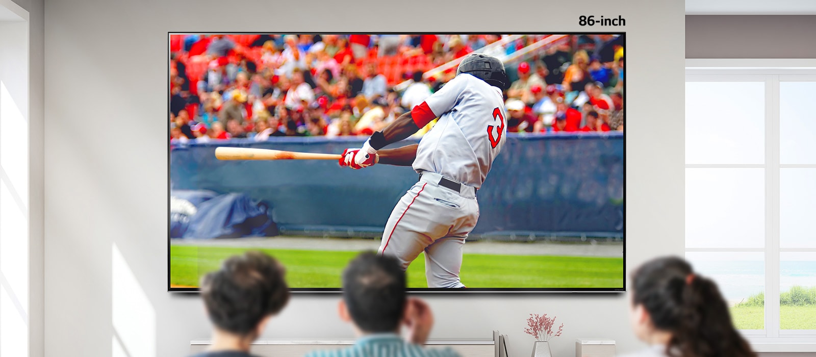 Een scrolbaar beeld van drie mensen die honkbal kijken op een grote aan de muur gemonteerde tv. Als je van links naar rechts scrolt, wordt het scherm groter.