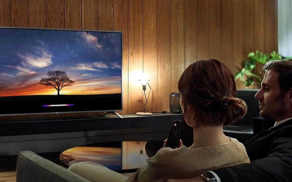 A couple watches the LG TV in their home cinema room.