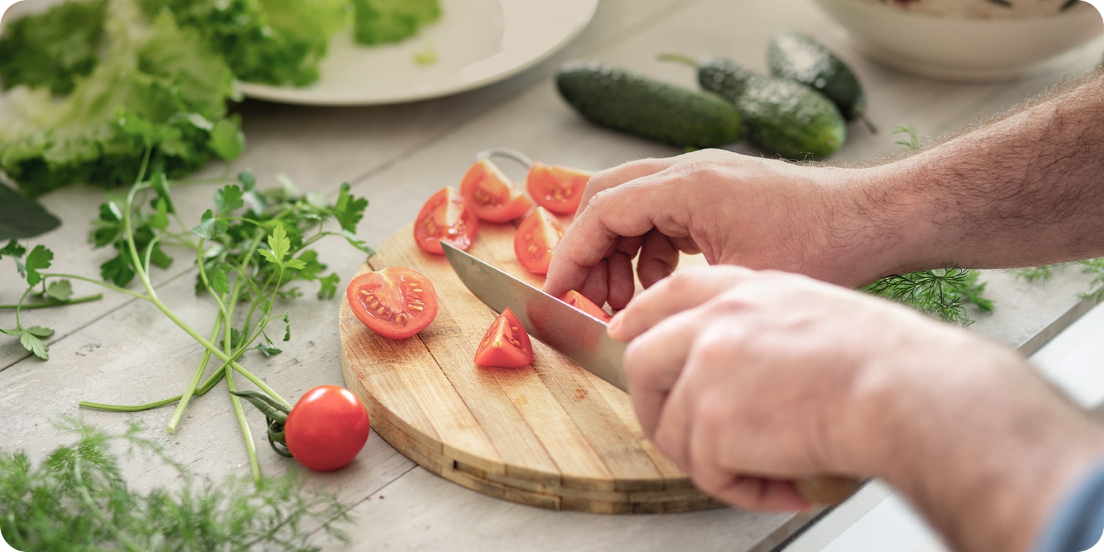 Bilde av kutting av tomater på et skjærebrett med en kniv.