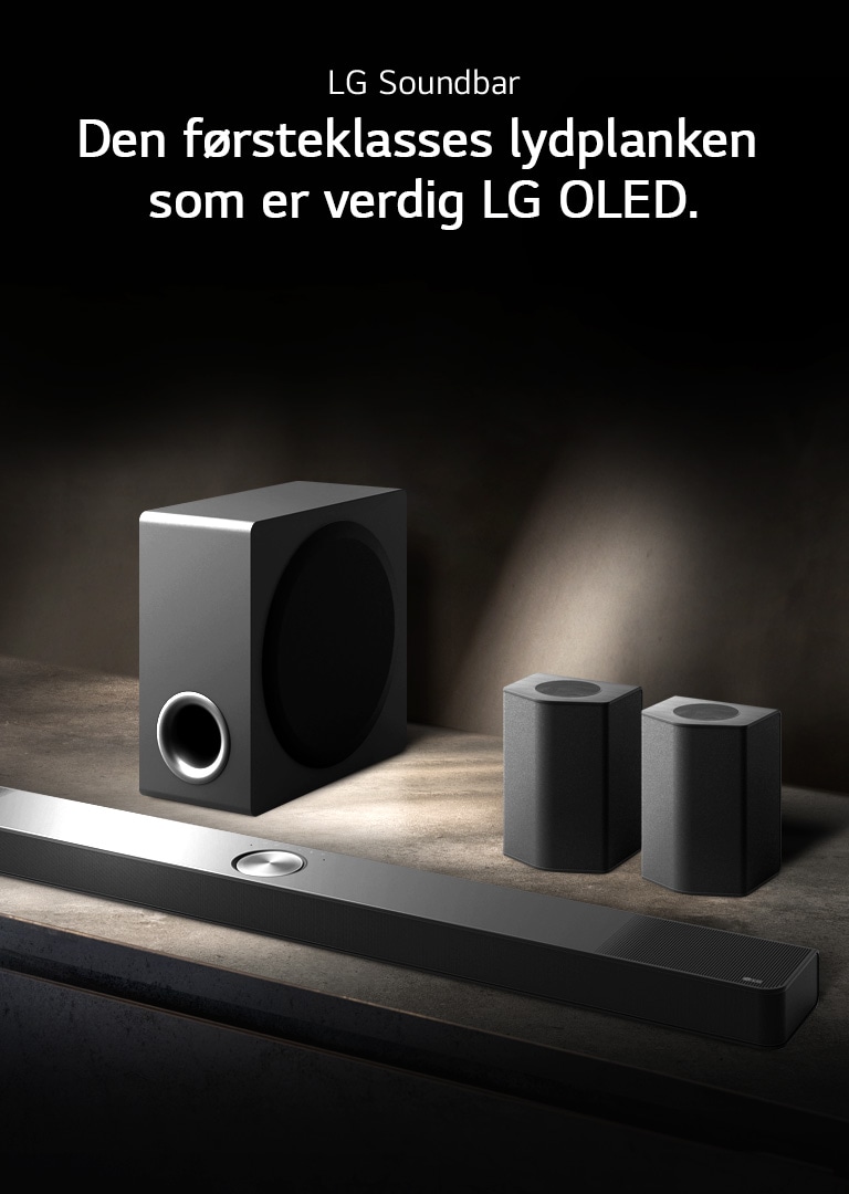 LG Soundbar, bakhøyttalere og subwoofer er plassert i et vinklet perspektiv på en brun trehylle i et svart rom, innhyllet i mørke med lys som bare kaster over lydanlegget.