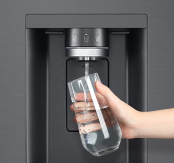 A person is getting water from the refrigerator dispenser in a cup