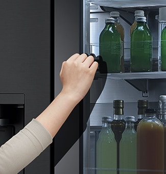 The front view of a black glass InstaView refrigerator with the light on inside. Hands tapping on InstaView screen.