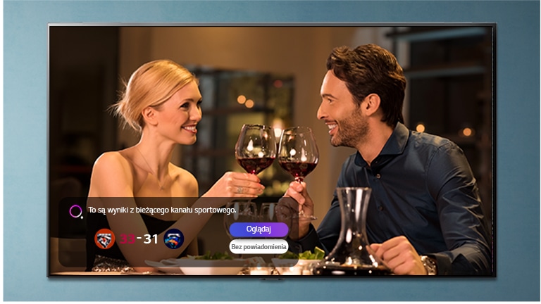 Un uomo e una donna fanno tintinnare gli occhiali su uno schermo TV che mostra una notifica sportiva