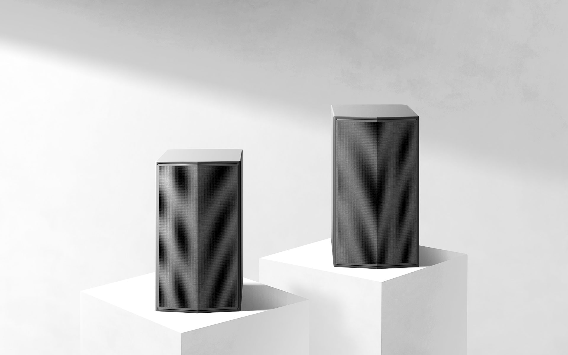 Rear speakers in a white space with each sitting on a marble podium. 