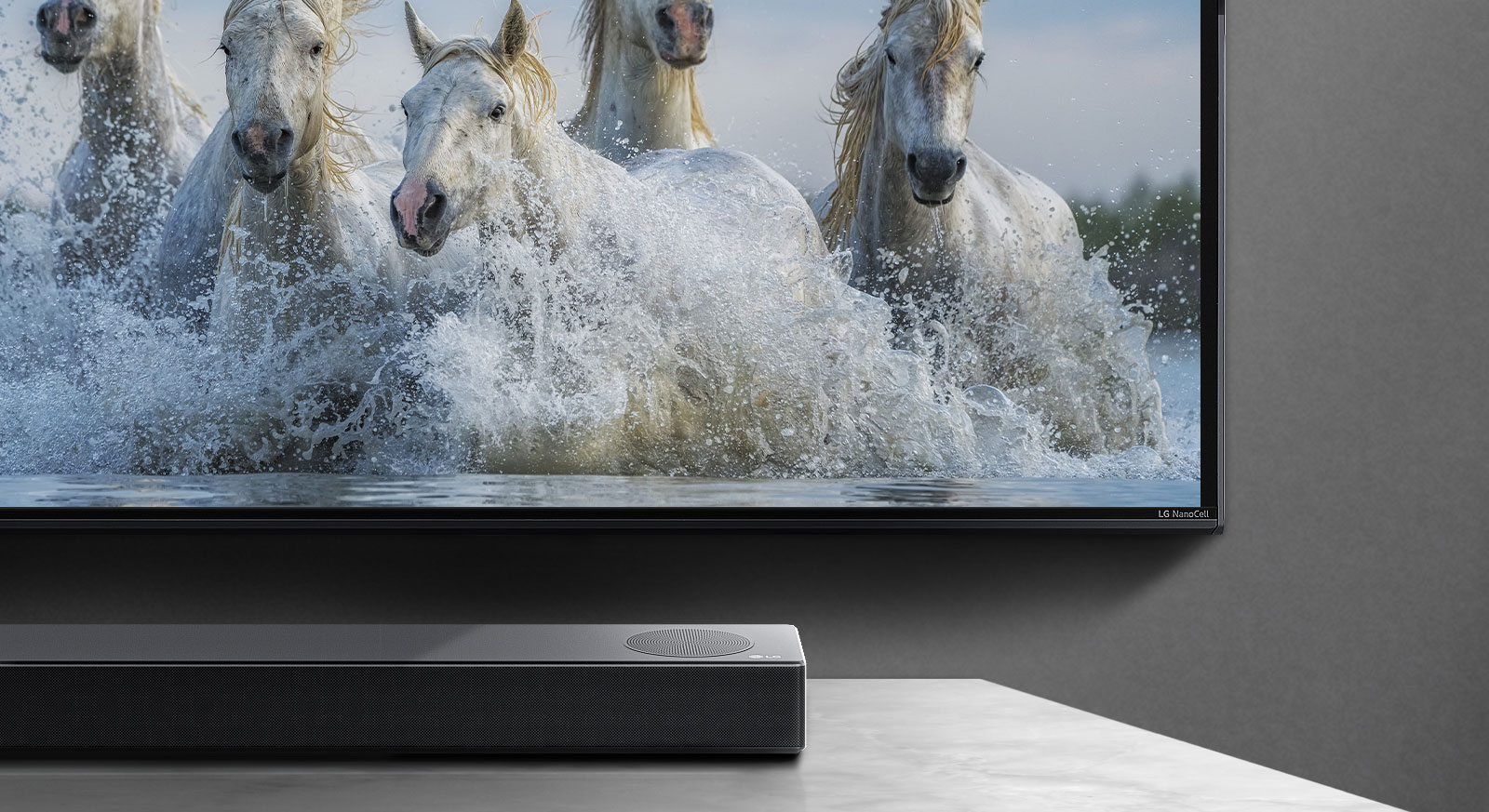 Polovina donjeg dela ekrana i polovina Soundbar zvučnika. Na televizoru se prikazuju beli konji koji trče iznad vode. 