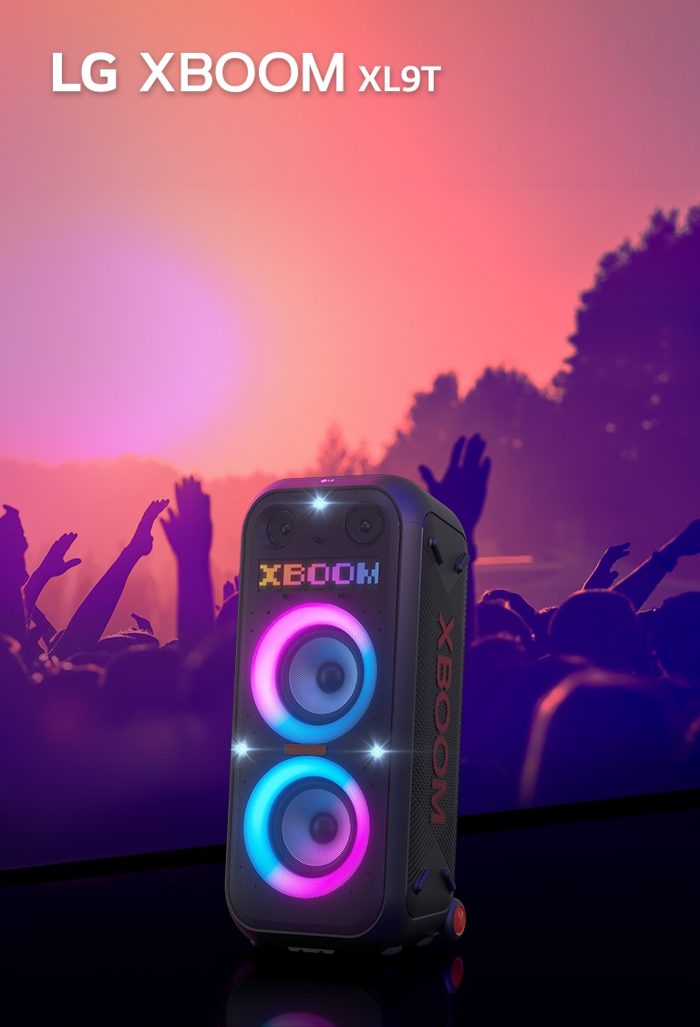 LG XBOOM XL9T расположена на поверхности с диагональным обзором. Включена многоцветная подсветка, а на дисплее появляется слово «XBOOM». За колонкой — силуэты людей, наслаждающихся вечеринкой.