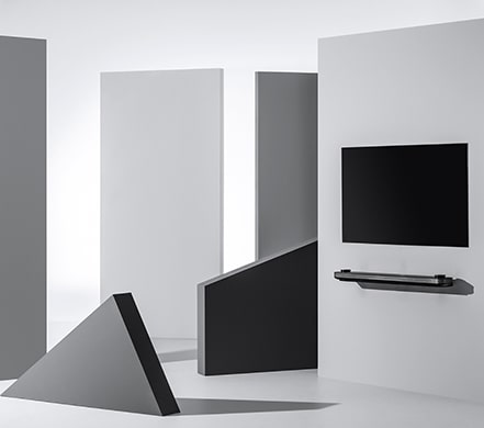 Телевизор LG SIGNATURE OLED TV W висит на стене, окруженный геометрическими фигурами