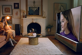 Оливия Палермо смотрит на себя на телевизоре LG SIGNATURE OLED 8K в гостиной.