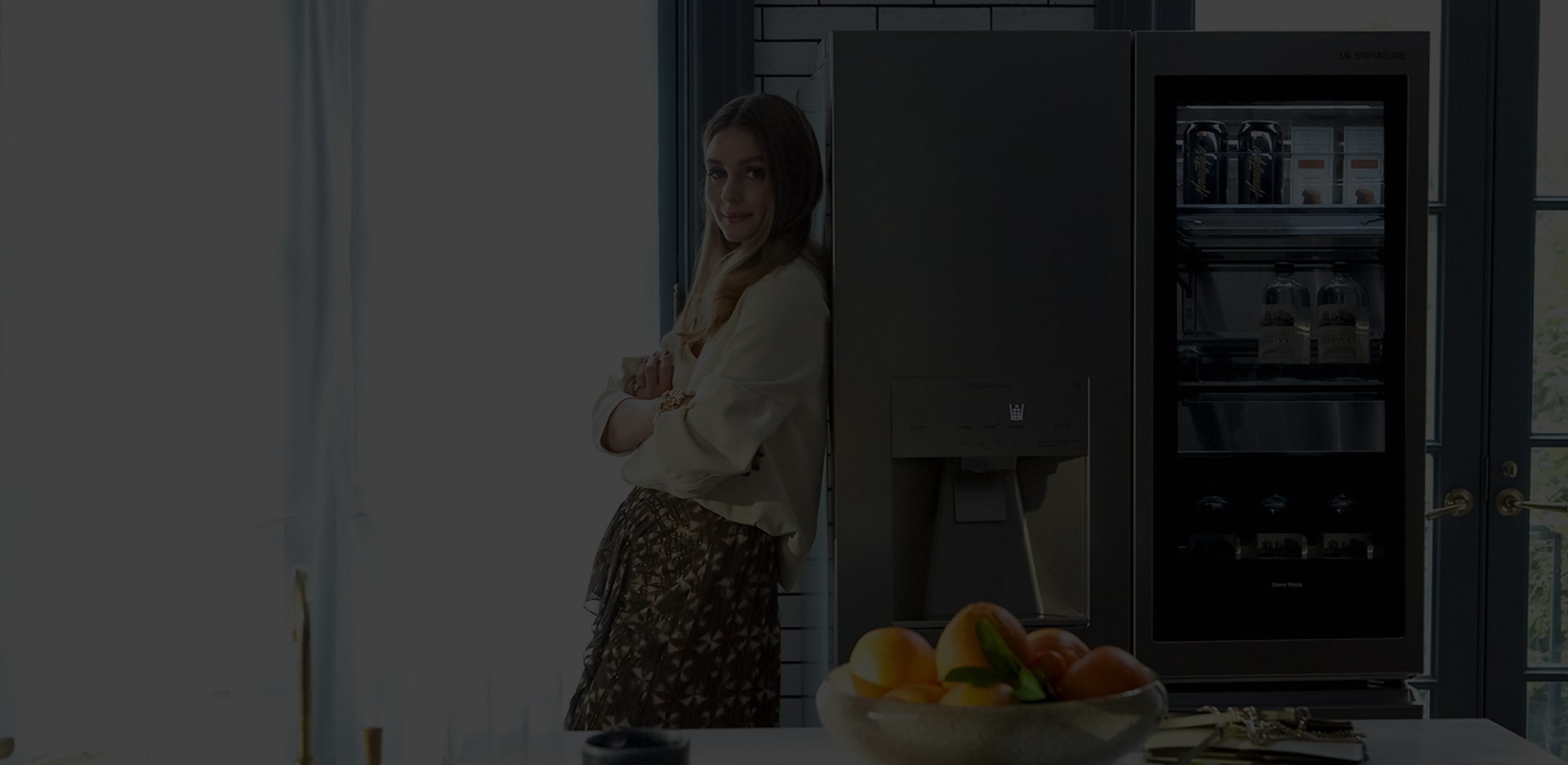 Оливия Палермо стоит, прислонившись к холодильнику LG SIGNATURE.