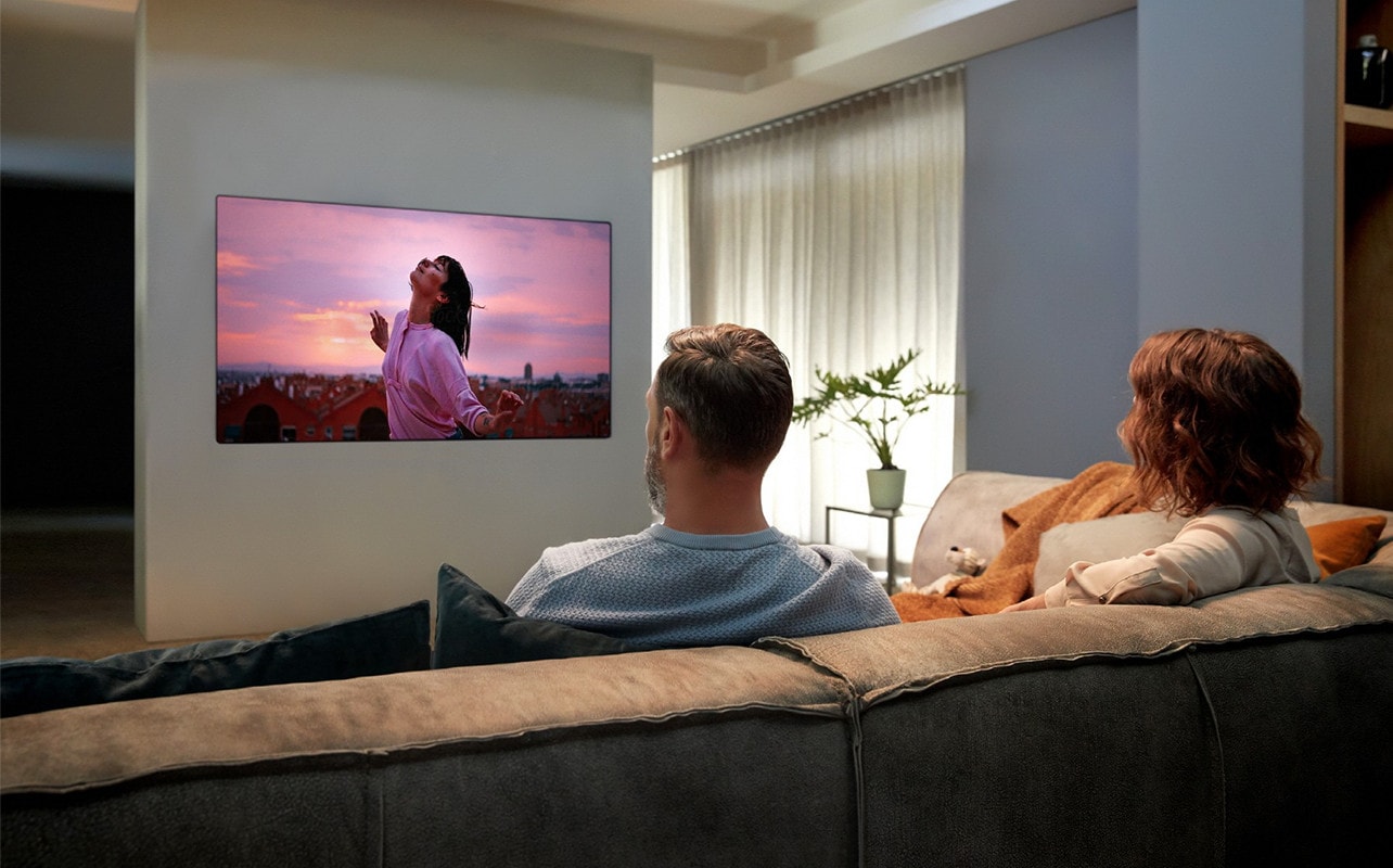 пара смотрит телевизор на диване в гостиной