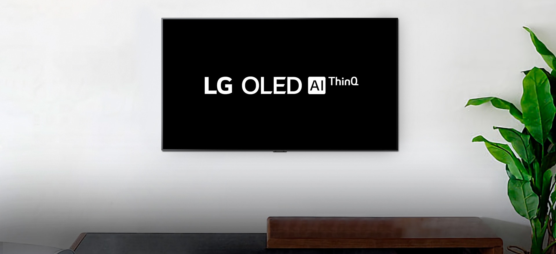 Настенный телевизор, показывающий логотип LG OLED AI ThinQ на черном фоне