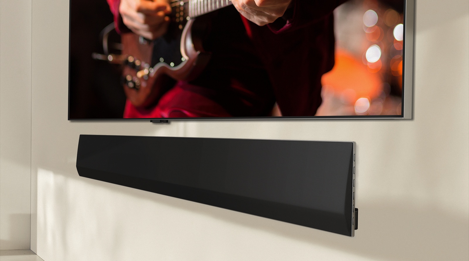 Pohľad zboku na spodnú časť panela LG Soundbar a LG TV, ktoré sú pripevnené na stenu.