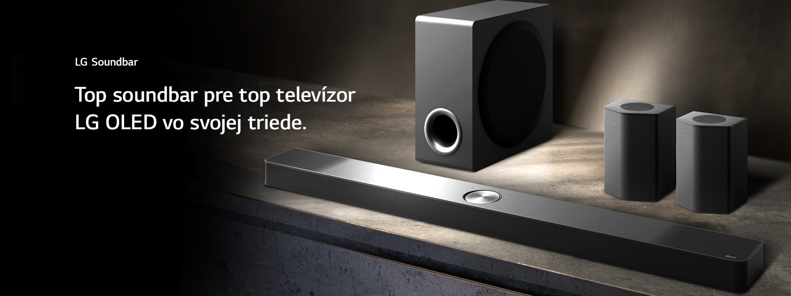 LG Soundbar, zadné reproduktory a subwoofer sú umiestnené v šikmej perspektíve na hnedej drevenej polici v čiernej miestnosti, obklopené tmou, pričom svetlo dopadá len na zvukový systém.